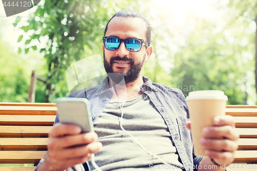 Image of man with earphones and smartphone drinking coffee