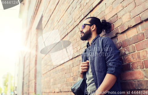 Image of man with backpack standing at city street wall