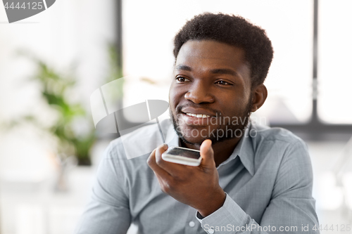 Image of businessman records voice by smartphone at office