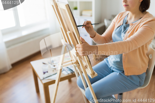 Image of artist with easel and brush painting at art studio