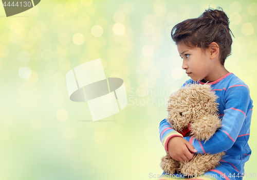 Image of sad little girl with teddy bear over green lights