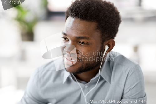Image of man with earphones listening to music at office