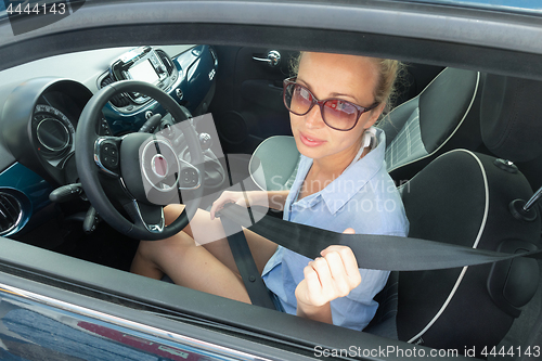 Image of Safety first. Beautiful blonde caucasian lady fastening car seat belt.