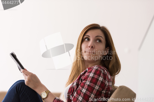 Image of woman sitting on sofa with tablet computer