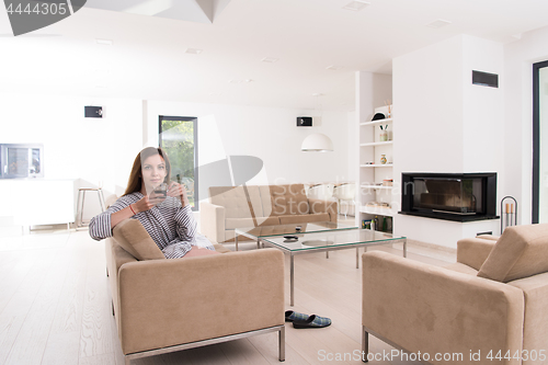 Image of young woman in a bathrobe enjoying morning coffee