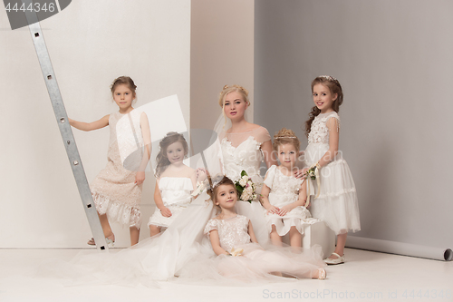 Image of Little pretty girls with flowers dressed in wedding dresses