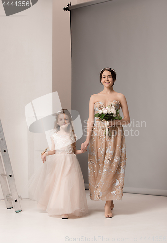 Image of Little pretty girls with flowers dressed in wedding dresses