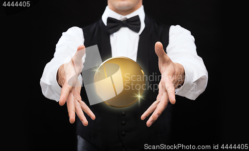 Image of close up of magician with golden coin over black