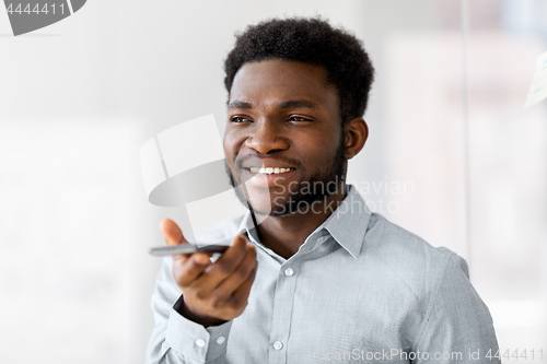 Image of businessman records voice by smartphone at office