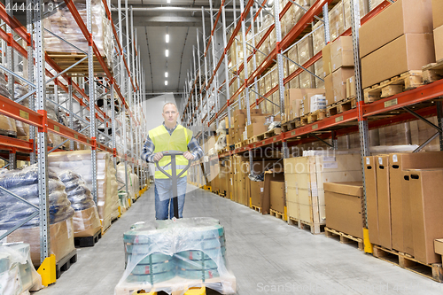 Image of warehouse worker carrying loader with goods