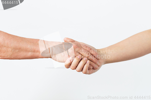 Image of close up of senior and young woman holding hands