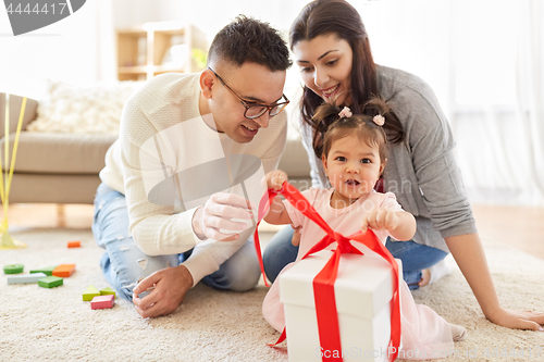 Image of baby girl with birthday gift and parents at home