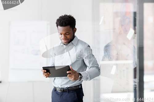 Image of smiling businessman with tablet pc at office