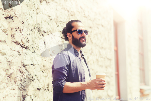 Image of man drinking coffee from paper cup on street