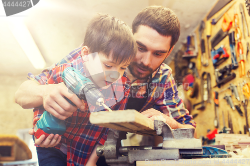 Image of father and son with drill working at workshop