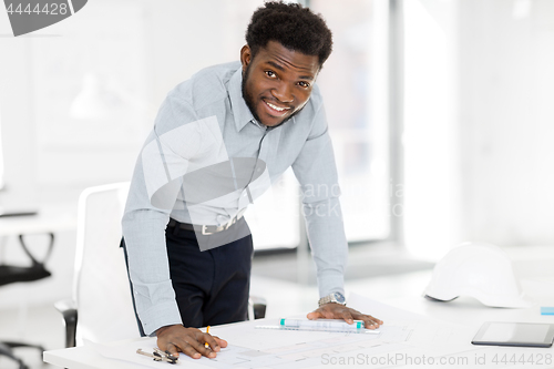 Image of smiling african architect with blueprint at office