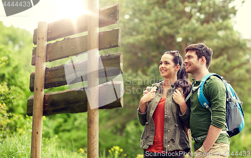 Image of smiling couple at signpost with backpacks hiking