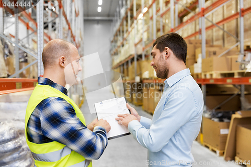 Image of worker and businessman with clipboard at warehouse