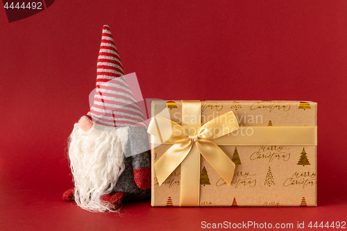 Image of Christmas decoration with a gnome and a gift box on red backgrou