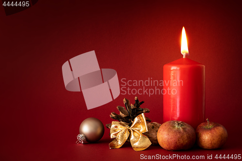 Image of Christmas decoration with a burning candle on red background