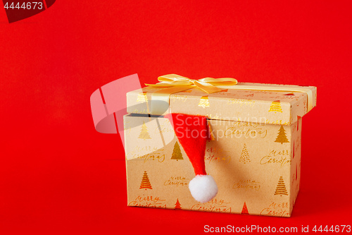 Image of Christmas gift box with Santa Claus hat on red background