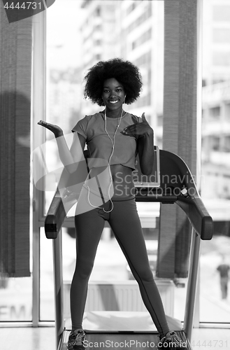 Image of afro american woman running on a treadmill