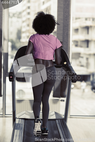 Image of afro american woman running on a treadmill