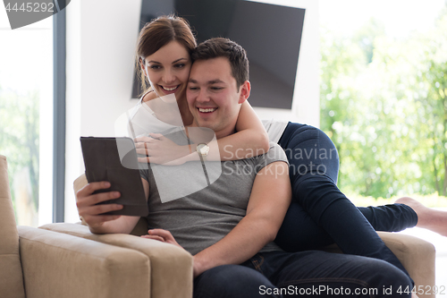 Image of couple relaxing at  home with tablet computers