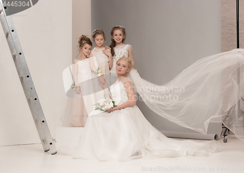 Image of Little pretty girls with flowers dressed in wedding dresses