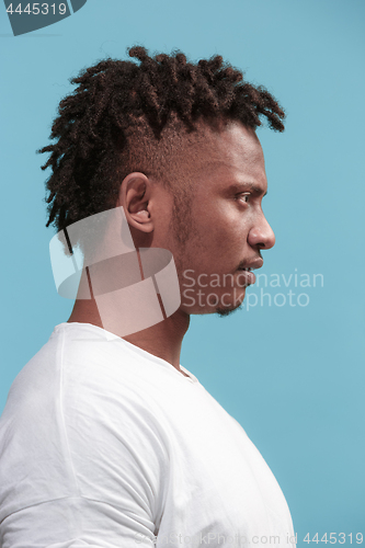 Image of The surprised business Afro-American man standing and looking blue background. Profile view.