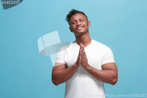 Image of The happy business afro-american man standing and smiling against blue background.