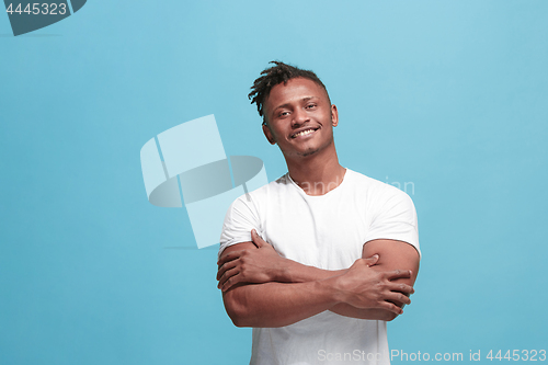 Image of The happy business afro-american man standing and smiling against blue background.