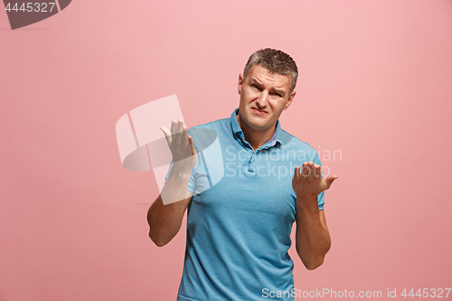 Image of Beautiful male half-length portrait isolated on pink studio backgroud. The young emotional surprised man