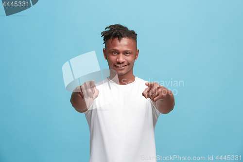 Image of The happy afro-american businessman point you and want you, half length closeup portrait on blue background.