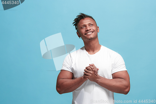 Image of The happy business afro-american man standing and smiling against blue background.
