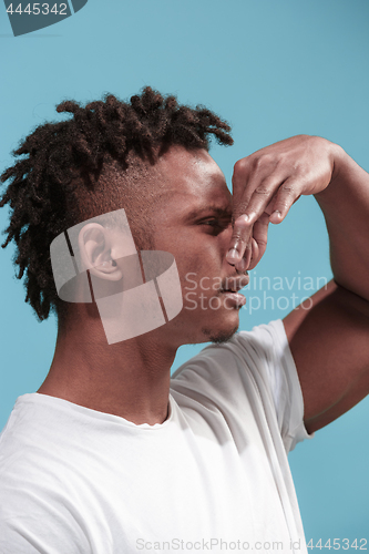 Image of Young man with disgusted expression repulsing something, isolated on the blue