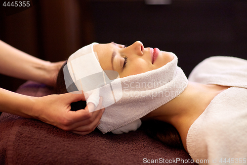 Image of woman having face massage with towel at spa