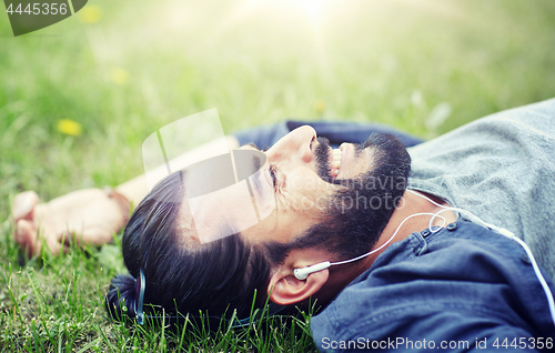 Image of man with earphones listening to music on grass