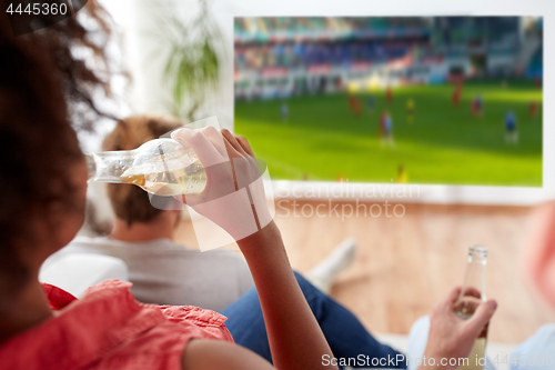 Image of woman drinking beer and watching soccer game