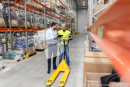 Image of businessman with clipboard and loader at warehouse