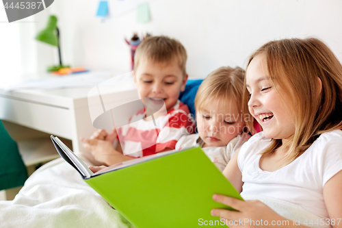 Image of little kids reading book in bed at home