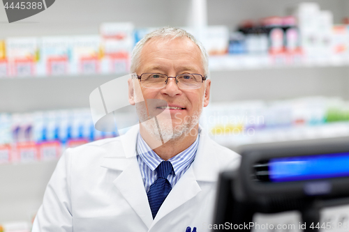 Image of senior apothecary at pharmacy cash register