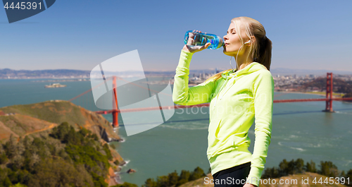 Image of woman drinking water after doing sports outdoors