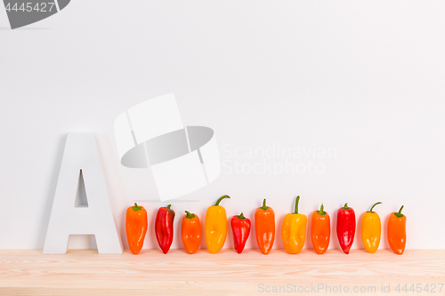 Image of Colorful peppers and letter A on wooden surface