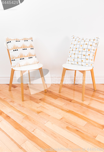 Image of Stylish chairs with ornamental cushions on hardwood floor