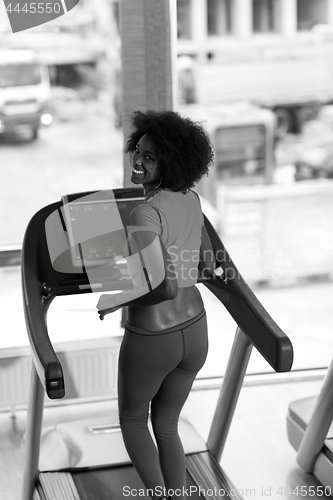 Image of afro american woman running on a treadmill