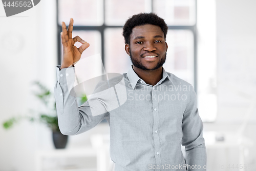 Image of african american businessman at office showing ok