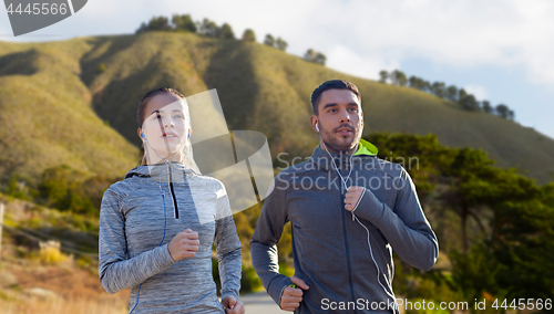 Image of couple with earphones running over big sur