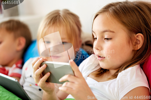 Image of little kids with smartphone in bed at home