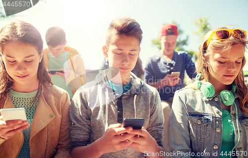 Image of group of teenage friends with smartphones outdoors